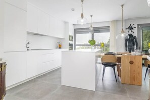 A modern kitchen with white cabinetry, a central island, and pendant lighting. - Exquisite home walking to the beach. (Mijas)