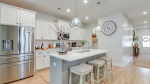 A modern kitchen with white cabinets, stainless steel appliances, and a central island with bar stools.