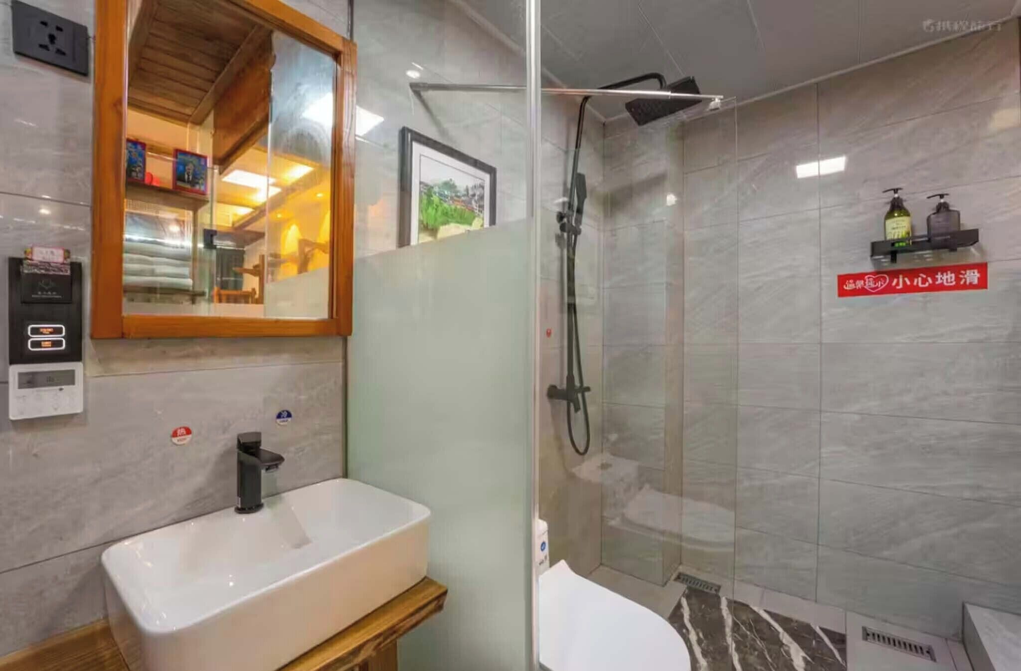 A bathroom with a white sink, a glass-enclosed shower, and a wooden-framed mirror.