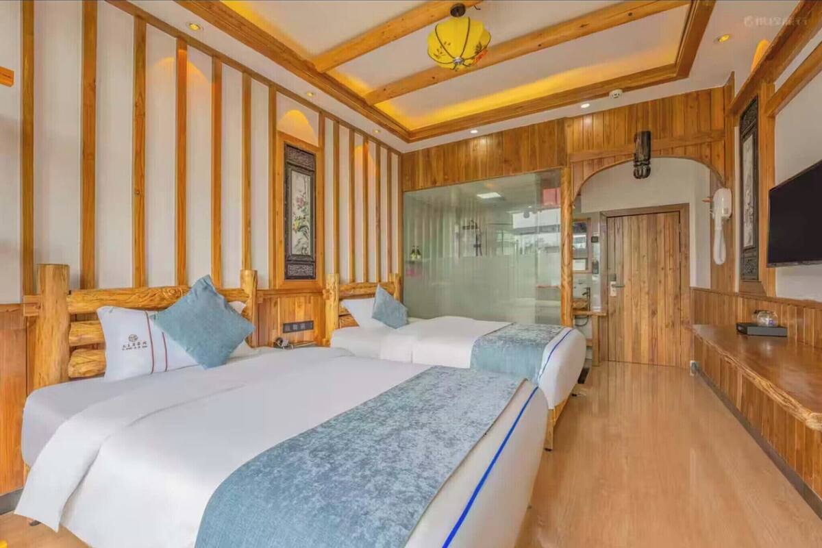 Ein Hotelzimmer mit Holzwandverkleidung, einem großen Bett, einem Fernseher und einer Glaskabine.