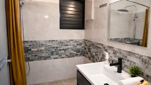 Un baño moderno con ducha, un espejo grande y un tocador con lavamanos.