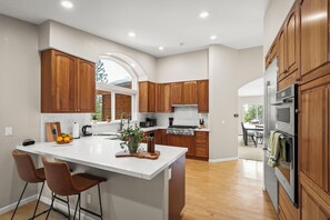 A modern kitchen with wooden cabinets, a large island with bar stools, and a view to the dining area. - Lake View 4BR in Incline Village | Deck & Fireplace (Incline Village)
