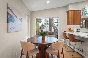 A modern kitchen with a wooden dining table, beige chairs, and a view of a snowy mountain through large windows. - Lake View 4BR in Incline Village | Deck & Fireplace (Incline Village)