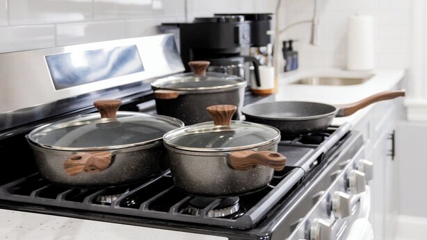 Een keuken met een fornuis, pannen en een koffiezetapparaat.