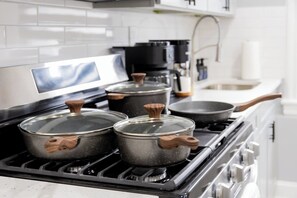 A kitchen with a stove, pots, and a coffee maker. - Spacious 3 Bedroom | Steps to Bus to NYC + Views (West New York)