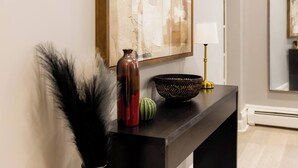 Een donkerhouten console tafel met decoratieve objecten, waaronder een vaas, een schaal en een lamp.