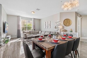 Un ampio soggiorno con zona pranzo, una grande finestra e un moderno lampadario.