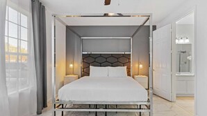 Una camera da letto moderna con un letto posizionato al centro sotto una testiera con motivi geometrici, affiancato da comodini con lampade.