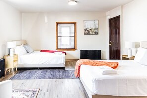 Una habitación de hotel con dos camas, una ventana, un radiador y un cuadro en la pared.