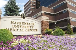 Señal del Hackensack University Medical Center frente a un jardín arbolado.