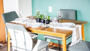 A dining table set with plates, glasses, and cutlery, surrounded by chairs, with potted plants on the table.