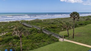 A coastal landscape with a pathway, palm trees, and the ocean. - Barefoot Trace 409 Direct Oceanfront with Private Balcony Overlooking St. Augustine Beach (St. Augustine)