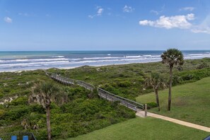 A coastal landscape with a pathway, palm trees, and the ocean. - Barefoot Trace 409 Direct Oceanfront with Private Balcony Overlooking St. Augustine Beach (St. Augustine)