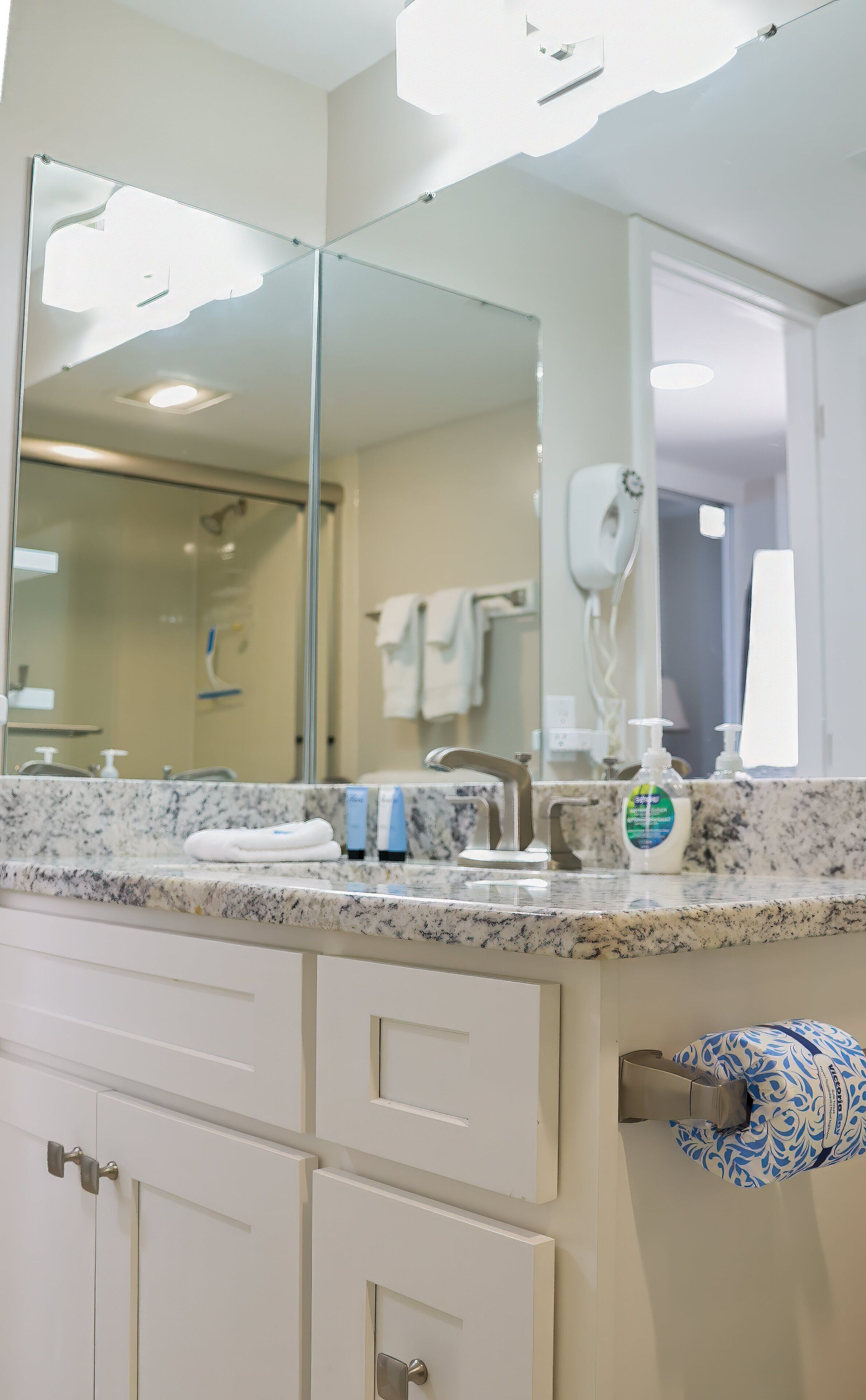 A bathroom with a marble countertop, a sink, a mirror, and a towel rack.