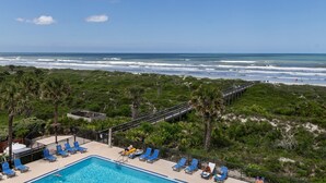 A pool with blue lounge chairs, a wooden deck, and a view of the ocean. - Barefoot Trace 409 Direct Oceanfront with Private Balcony Overlooking St. Augustine Beach (St. Augustine)
