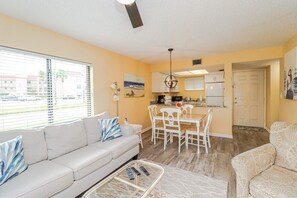 A living room with a sofa, a coffee table, and a dining area with chairs and a table. - Ocean Village Club A17 (St. Augustine)