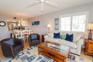 A living room with a sofa, armchairs, a coffee table, and a dining area with a table and chairs. - Ocean Village Club E22 (St. Augustine)