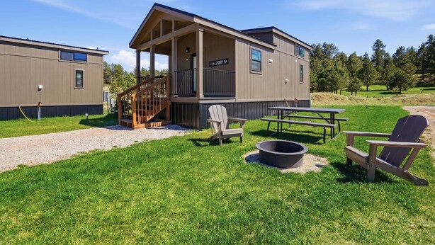 A two-story building with a covered porch, outdoor seating, and a fire pit. - Huckleberry Inn - 1 BD Cabin (Custer)