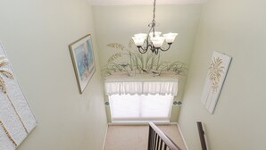 A staircase with a white railing, a chandelier, and a window with a white valance. - St Augustine Beach & Tennis Resort 611-Pet-Friendly Townhome! (St. Augustine)