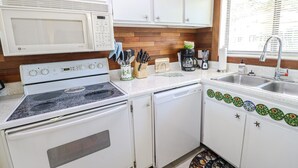 A compact kitchen with white cabinets, a stove, a microwave, a coffee maker, and a sink. - St Augustine Beach & Tennis Resort 611-Pet-Friendly Townhome! (St. Augustine)