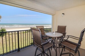 Ein Balkon mit Blick auf den Strand, ausgestattet mit einem runden Tisch und vier Stühlen.