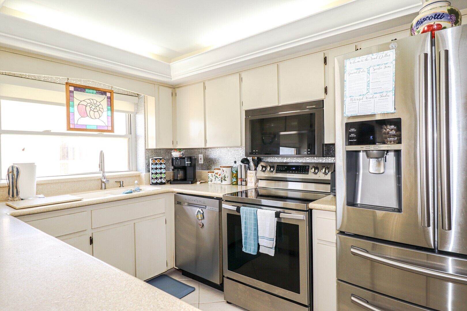 A modern kitchen with stainless steel appliances, a coffee maker, and a refrigerator with a water dispenser.