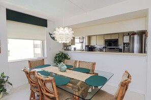 Een moderne keuken met een glazen eettafel, rieten stoelen en een decoratieve sculptuur van een vis.