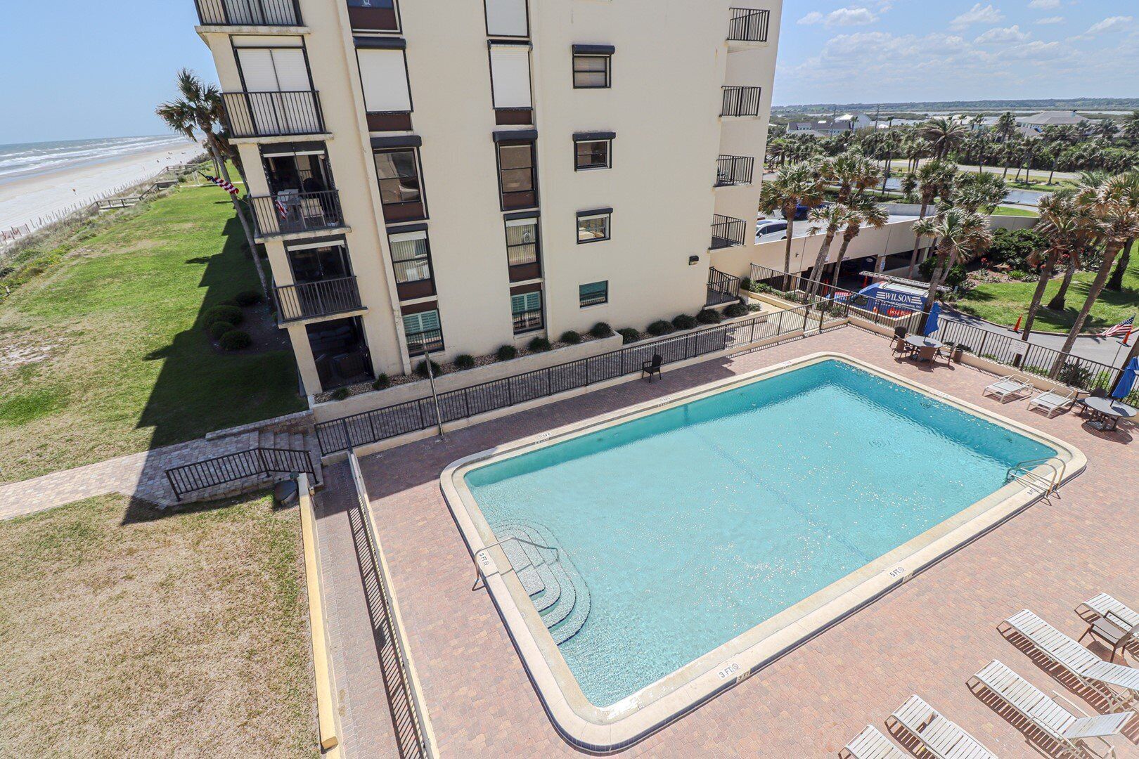 Et hotel med swimmingpool, udsigt til stranden og en parkeringsplads med skiltning for Wilson.
