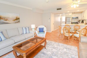 A living room with a sofa, coffee table, and dining area with chairs. - Remodeled Luxury Condo at Spanish Trace 238 (St. Augustine)
