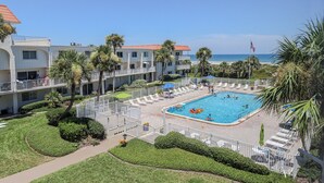 Ein Hotel mit Pool, umgeben von Palmen und Liegestühlen.