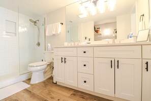 A modern bathroom with a glass shower enclosure, a white toilet, and a vanity with white cabinets and a mirror. - Anastasia Condos 311-Ocean View two bedroom condo with private balcony! (St. Augustine)