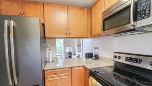 Una cocina con armarios de madera, un refrigerador de acero inoxidable, un microondas, un horno y un tostador.