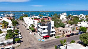 Uma cidade costeira com edifícios modernos, uma marina com barcos e vista clara para o mar.