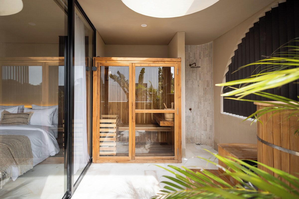 A bedroom with a bed, a wooden cabinet, and a shower area.