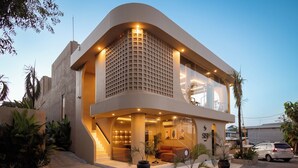 Un hotel moderno con fachada curva, ventanas grandes y una escalera que lleva a la entrada.