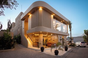 A modern hotel with a curved facade, large windows, and a staircase leading to the entrance. - SISI Wellness Villas (Pecatu)