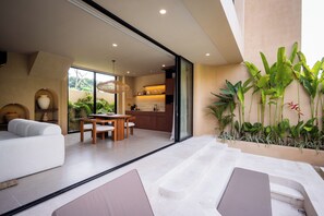 A modern interior with a sofa, dining table, and kitchen area visible through glass doors. - SISI Wellness Villas (Pecatu)