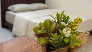 Une pièce comprenant un lit, une table en bois et un panier rempli de plantes vertes et de fleurs jaunes.