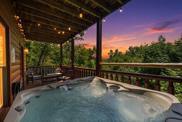 A hot tub on a wooden deck with a view of trees and a sunset. - Epic View | Family Cabin | Hot Tub + Fire Pit | Sleeps 12 | Near Pigeon Forge (Sevierville)