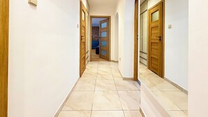 Um corredor com portas de madeira e chão de azulejos.