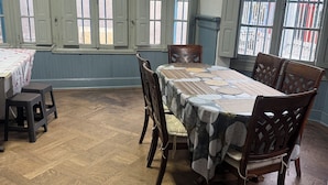 Un comedor con piso de madera en espiga, una mesa con mantel estampado y dos sillas de madera.
