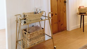 Habitació amb televisió penjada, una cadira de vimetera amb cistelles d'emmagatzematge, una porta de fusta i una taula petita amb una cistella.