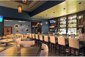 A bar area with multiple seating options, a well-stocked bar, and decorative wall elements.