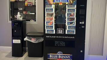 Un distributeur automatique de la marque Blue Bunny, avec un point d’eau et une poubelle à proximité.