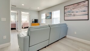A modern living room with a light blue sofa, a flat-screen TV, and a large abstract painting on the wall. - 4 Mi to Downtown Tampa! Urban Couples Retreat (Tampa)