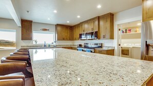 Una cocina con encimeras de granito, armarios de madera, electrodomésticos de acero inoxidable y una isla grande con taburetes de bar.