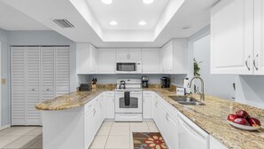 A modern kitchen with white cabinetry, a granite countertop, a built-in microwave, and a stainless steel sink. - Tranquil Sarasota Retreat Near Beaches, Pool & Nature Escape - Timberwood Villa #183 - Roelens (Sarasota)
