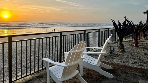 A beach view with two white Adirondack chairs and a railing. - Oceanview King Studio - Outside Terrace, Beachfront Pool & Tiki (Daytona Beach)