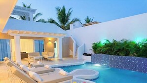 Un área de piscina moderna al aire libre con sillones de descanso, un jacuzzi y un bar con bebidas.