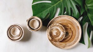 Trois bols en céramique ornés d’un motif en spirale, disposés sur une surface blanche, avec une grande feuille verte en arrière-plan.